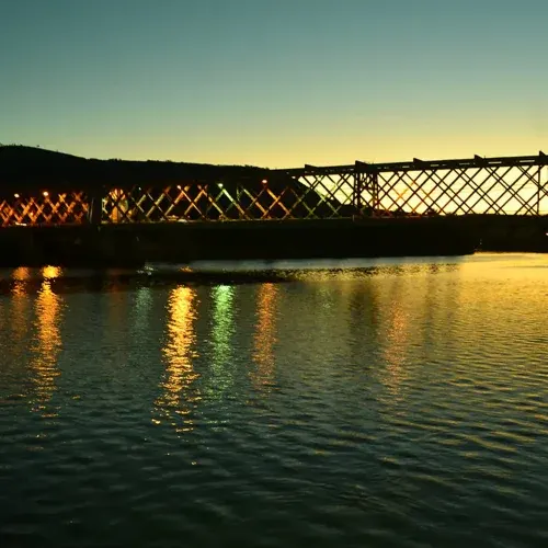 Ponte Dom Pedro II iluminada ao anoitecer, refletida nas águas do Rio Paraguaçu entre Cachoeira e São Félix