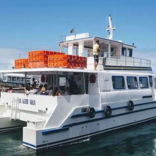 Lateral do catamarã Ilha Bela III, com tripulante no convés superior e boias salva-vidas empilhadas