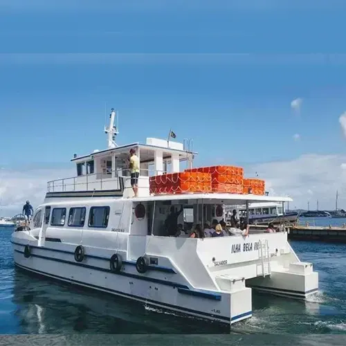 Catamarã Ilha Bela III atracado, com passageiros a bordo e boias salva-vidas no convés superior