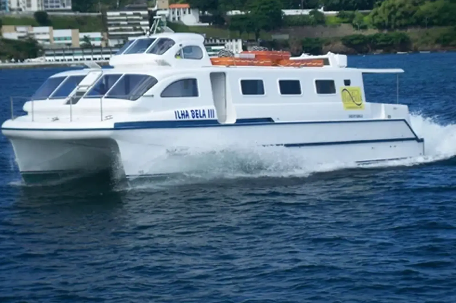 Catamarã Ilha Bela III navegando na Baía de Todos os Santos, com a orla de Salvador ao fundo