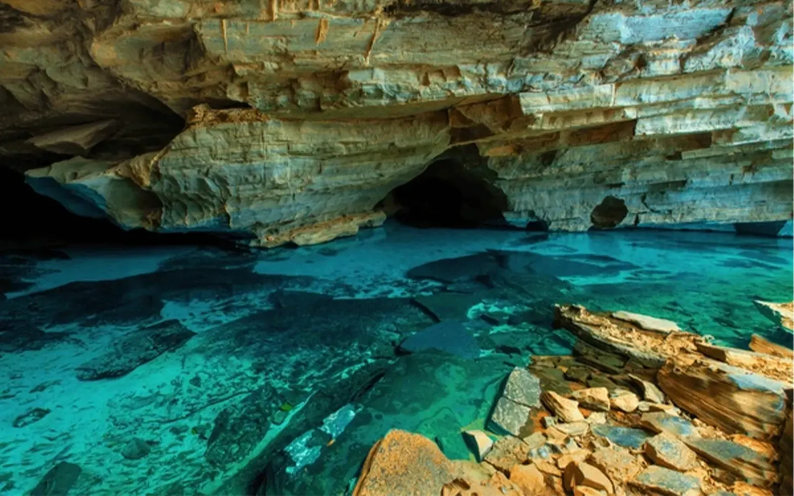 Gruta da Chapada Diamantina com água azul-turquesa transparente sobre o fundo de pedra