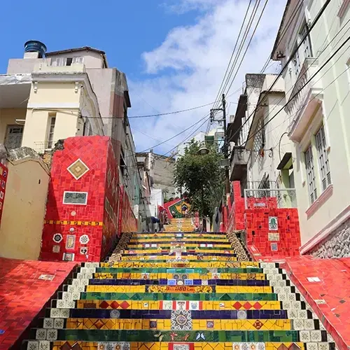 Escadaria revestida de azulejos coloridos entre casarões