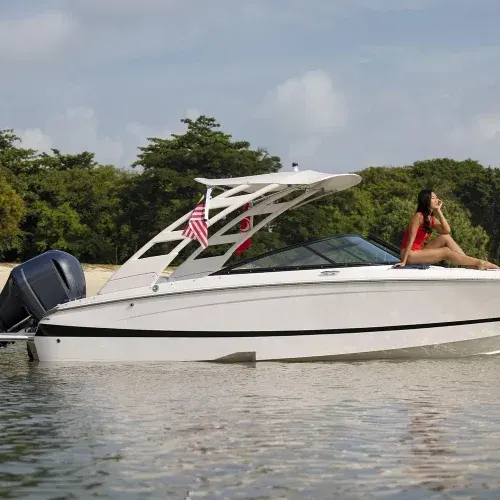 Lancha branca ancorada junto a um banco de areia, com a vegetação da ilha ao fundo