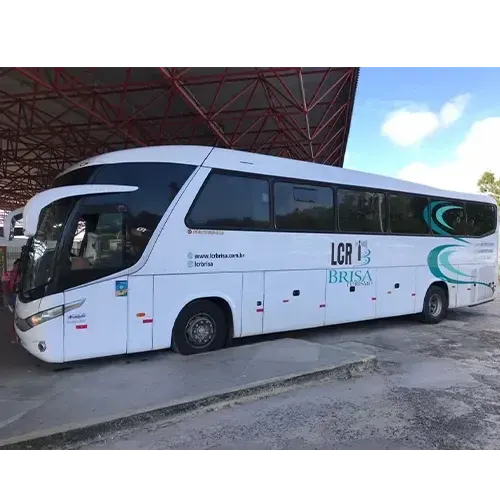 Ônibus rodoviário branco da LCR Brisa parado sob a cobertura de um terminal