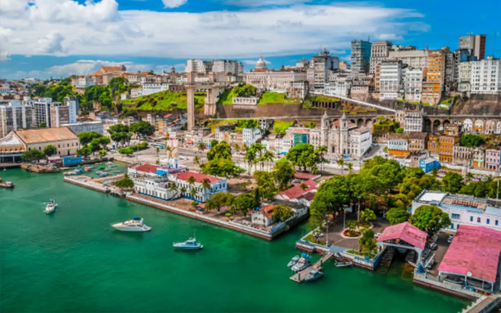 Vista aérea da Cidade Baixa de Salvador, com o Elevador Lacerda, o Mercado Modelo e barcos na Baía de Todos os Santos